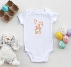 Baby First Easter.   Gorgeous Easter Bunny design for baby.   The sleep suit/romper is made of a lovely soft 100% cotton, it has long sleeves and feet. And Our bodysuit/vest is also of a soft 100% cotton, this has short sleeves.        Both come in these Sizes: 0-3months 3-6 months 6-12 months 12-18 months Style:  body suit, sleep suit Returns: Due to the personalised nature of the product we do not except returns, unless damaged.  But any problems please message us asap Cute White Onesie For Loungewear, Cute Cotton Onesie For Easter, Playful White Bodysuit As A Gift, Playful White Bodysuit Gift, Playful White Bodysuit As Gift, White Long Sleeve Onesie For First Birthday, White Long Sleeve Onesie Gift, Easter Templates, Bunny Designs