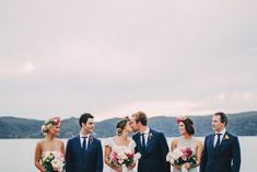 a group of people standing next to each other in front of a body of water