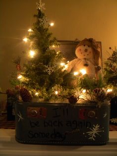 a teddy bear sitting on top of a christmas tree in a tin with lights around it