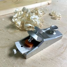 a small metal object sitting on top of a wooden table next to some wood shavings