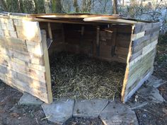 an outhouse made from pallet wood with the door open and straw in it