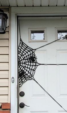 a spider web on the front door of a house with two lanterns attached to it