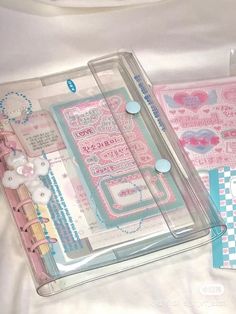 two clear cases with buttons and other items in them on a white sheeted surface