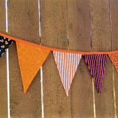 an orange and black banner hanging from a wooden fence with polka dots on the bottom