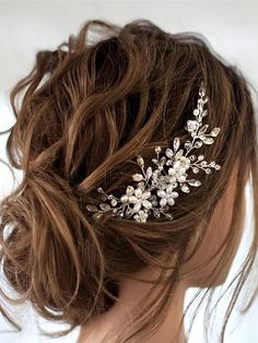 a woman wearing a bridal hair comb with flowers on it's head and long brown hair