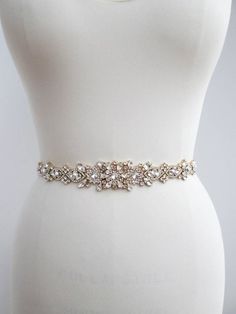 This floral belt design is made with Swarovski crystals set in fancy gold settings. The crystal design measures 1 3/8 wide at the widest point and 28 long. Available with grosgrain, organza or satin ribbon and in gold or silver finish. - This belt is fitted and it is finished with the Elegant Gold Bridal Accessories With Sashes, Gold Rhinestone Party Belt, Formal Bridal Belt With Crystal Sashes, Formal Crystal Bridal Belt With Sashes, Elegant Rhinestone Belts For Formal Occasions, Elegant Gold Belt For Party, Gold Embroidered Belt Sash For Parties, Gold Embroidered Sash For Party, Elegant Gold Sashes With Embroidered Belt