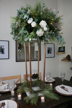 a dining room table decorated with greenery and candles