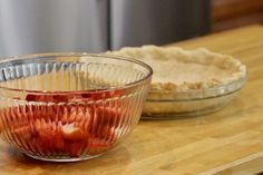 two bowls filled with food sitting on top of a wooden table next to an uncooked pie crust