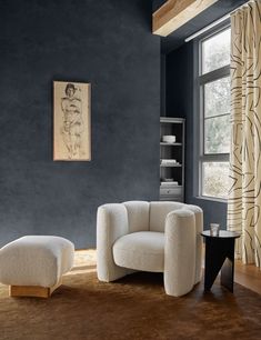 a living room with blue walls and a white chair in the corner next to a window