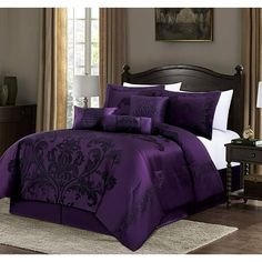 a bed with purple comforters and pillows in a room