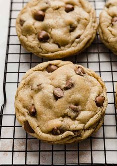 four chocolate chip cookies cooling on a wire rack, with one cookie in the middle