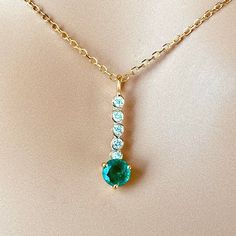 This is part of Chairish’s Fine Jewelry assortment.  The Emerald and Diamond Lariat Gold Drop Necklace Pendant features a blend of elegance and sophistication. Crafted from fourteen karats of white and yellow gold, this trending lariat necklace pendant exudes luxury. Here are the key details: Gemstones: The pendant showcases a single round emerald, bezel set and weighing 0.40 carats. The emerald exhibits a hue tone resembling grass green, adding a vibrant touch to the piece. Additionally, there Elegant Yellow Gold Lariat Necklace With Round Pendant, Elegant Long Drop Lariat Necklace With Gemstone, Elegant Yellow Gold Lariat Necklace With Gemstone, Gold Drop Necklace, Diamond Bar, Diamond Chain, Grass Green, Diamond Drops, Key Details