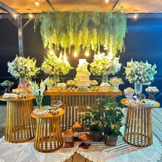 a table topped with lots of cakes and flowers on top of a wooden table covered in greenery