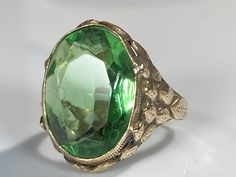 "Beautiful green paste gemstone ring from the Arts & Crafts movement of the late 19th century. The beautiful ring features classic Arts & Crafts handmade fashioning, with subdued floral detail reminiscent of the Art Nouveau period to which Arts & Crafts overlaps. The oval faceted green paste is bezel set and measures 18x6x13.6mm north to south. The gold tests at around 6K and can be easily sized up or down several sizes. All hallmarks carefully preserved during sizing or restoration. Please allo Art Deco Green Emerald Ring With Rose Cut Diamonds, Classic Green Jewelry With Rose Cut Diamonds, Art Deco Emerald Ring With Rose Cut Diamonds, Oval Green Rose Cut Diamond Rings, Antique Yellow Gold Cabochon Emerald Ring, Antique Yellow Gold Emerald Cabochon Ring, Victorian Yellow Gold Emerald Ring, Formal Green Cabochon Emerald Ring, Victorian Emerald Ring In Yellow Gold