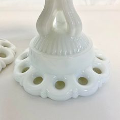 a white vase sitting on top of a table next to two smaller pieces of pottery