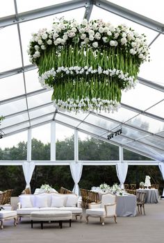 an indoor tent with couches, tables and flowers hanging from it's ceiling