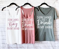 "If you're on the hunt for beach bachelorette party shirts, these Sun Sand and A Ring on My Hand Shirts and matching Sun Sand and A Drink in My Hand shirts are the PERFECT pick for beach bachelorette tank tops! Mix and match the different styles for your wedding party. WHITE TEXT is used by Default or Colored Shirts. ROSE TEXT is used by Default for white Shirts. If you prefer BLACK text for the bride's shirt, please include that in the NOTES section of checkout! HOW TO ORDER 1. Select your quan White Summer Top For Hen Party, Beach Fitted Tank Top With Letter Print, Fitted Letter Print Tank Top For Beach, White T-shirt For Hen Party In Summer, White T-shirt For Summer Hen Party, Summer Bachelorette Party T-shirt With Letter Print, Summer Fitted T-shirt For Bachelorette Party, Fitted T-shirt For Summer Bachelorette Party, Casual Summer Tops For Bachelorette Party