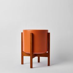 an orange planter sitting on top of a wooden table next to a white wall