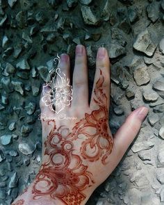 a person's hand with henna tattoos on it and rocks in the background