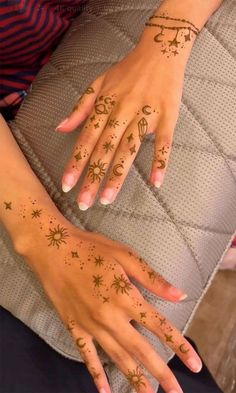 a woman's hand with tattoos on it and stars painted on her fingers,