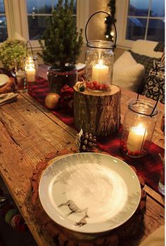 a wooden table topped with a white plate covered in candles next to a tree stump