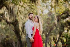 a man and woman standing in front of trees