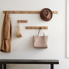 a hat, coat rack and purse hanging on a wall with the words west elm written below it