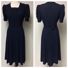 A 1940's Navy Gabardine Swing Dress, with a square neckline, buttonhole detail. Center front has horizontal pin tucks, wrapping around  the waist and below the waist. Side front has vertical pin tucks, shirred below the bust. The upper back dress is fitted with waistline darts, top stitched waistline,  a center back metal zipper and self made back ties.  There are pleats at the top of the sleeves and stitched tucks at the bottom of sleeves. The sleeves have padding. There are 5 gores in the front skirt, and 4 gores in the back. A great Swing dress! Measurements:      Shoulder to shoulder: 13 1/2"      Bust: 38"      Waist: 28"      Bottom of pin tucks: 31"      Hips (7" below waist): 37"      Front shoulder to hem: 42 1/2"      Shoulder to bottom of tucks: 19"      Sleeve length from shoul Elegant Fitted Vintage Dress In Solid Color, Elegant Solid Color Fitted Vintage Dress, Classic Vintage Dress With Fitted Bodice For Formal Occasions, Classic Fitted Vintage Dress For Formal Occasions, Classic Tailored Dresses With Button Closure, Classic Vintage Dress With Short Sleeves And Fitted Bodice, Classic Vintage Dress With Fitted Bodice And Short Sleeves, Classic Fitted Dresses For Vintage Fashion, Vintage Dresses With Fitted Waist For Formal Occasions