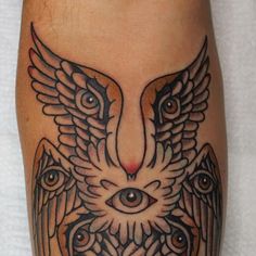 an owl tattoo on the leg with eyes and wings around it's head is shown