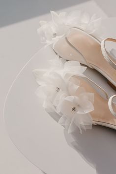 a pair of white shoes with flowers on the heel and heels are sitting on top of a plate