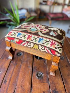 a wooden bench with a colorful foot rest on it