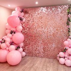 pink balloons and greenery are arranged in the corner of a room that is decorated with sequins