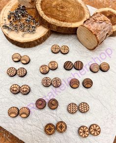 wooden buttons and chains laid out on top of a piece of paper next to some wood slices