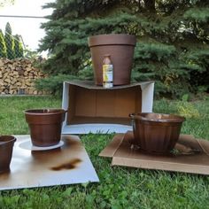 three pots sitting on top of cardboard in the grass