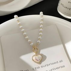 Drape yourself in elegance with this Coquette Heart Pearl Necklace. Lustrous pearls meet a charming heart pendant, creating a timeless piece that adds a romantic glow to any ensemble. Perfect for those seeking a blend of classic grace and endearing charm. Coquette aesthetic Heart shaped pearl with rhinestone pendant Pearl beaded design Zinc alloy Coquette Pearl Necklace, Coquette Heart, Heart Pearl Necklace, Aesthetic Heart, Bead Designs, A Romantic, Pearl Beads, Timeless Pieces, Heart Pendant