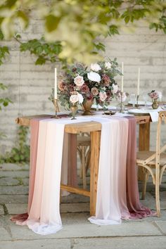 the table is set with pink and white linens, candles, and flowers on it