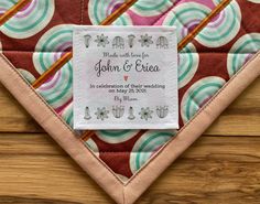 a close up of a quilt on a wooden surface with a label that reads made with love for john & erica