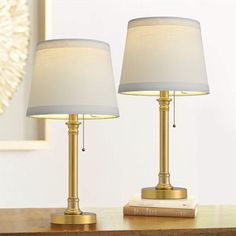 two lamps sitting on top of a wooden table next to a white and gold lamp