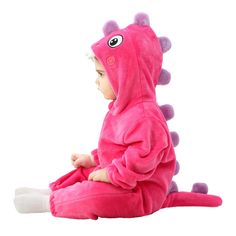 a baby sitting on the ground wearing a pink dragon costume