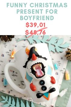 a coffee mug that has been decorated to look like a snowman with its mouth open and tongue out