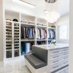 a walk in closet filled with lots of clothes and drawers next to a chandelier