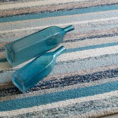 two blue plastic spoons sitting on top of a striped rug next to each other