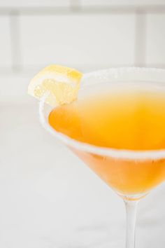 a close up of a drink in a glass with a slice of lemon on the rim