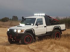 a white truck with lights on driving down a dirt road in the middle of nowhere