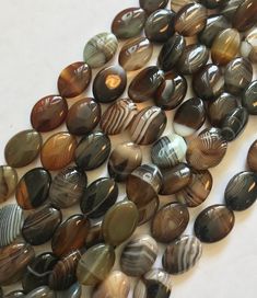 several brown and black agate beads on a white surface