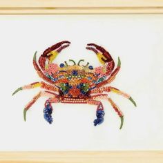 a colorful crab made out of beads is displayed in a wooden frame