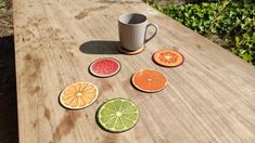 four slices of fruit are arranged on a wooden table with a coffee cup in the background