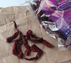 dried gourmet red peppers sitting on top of a piece of brown paper next to a bag