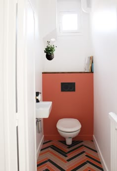 a white toilet sitting next to a sink in a bathroom under a window with a potted plant on top of it