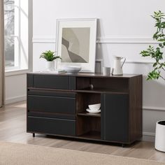 a black and brown sideboard with some plants on it next to a potted plant